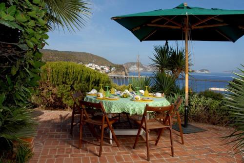 a table with chairs and an umbrella on a patio at La Limonaia a mare in Ponza