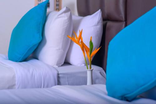 a vase with a flower on a bed with pillows at Cocoa Luxury Resort, Nyali, Mombasa in Mombasa