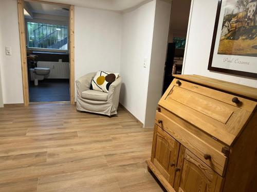 a living room with a chair and a wooden dresser at Charmante Souterrain Wohnung in Dortmund