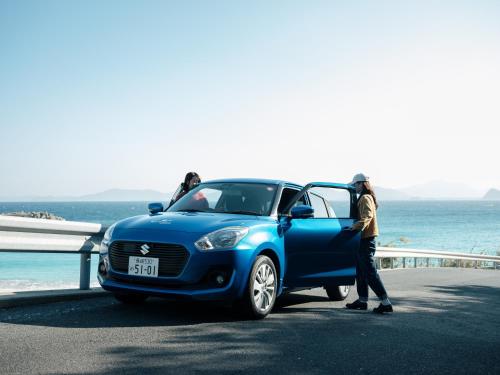a man standing next to a blue car next to the ocean at Colorit GOTO ISLANDS in Goto