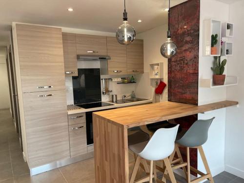 une cuisine avec un comptoir en bois et des chaises blanches dans l'établissement SUPERBE APPARTEMENT Terrasse PISCINE ET TENNIS, à Antibes