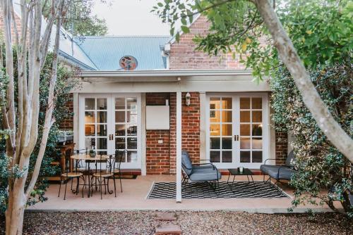 a brick house with a patio with chairs and tables at Kialla Cottage - An Idyllic Country Escape in Mudgee