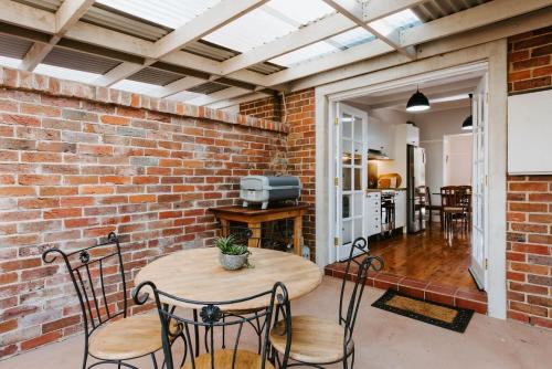 a room with a brick wall and a table and chairs at Kialla Cottage - An Idyllic Country Escape in Mudgee
