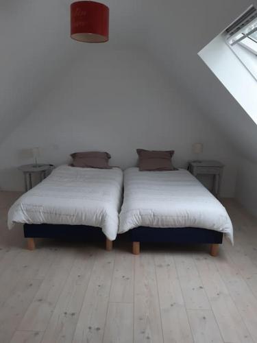 deux lits dans une chambre aux murs blancs et au parquet dans l'établissement La maison bord de mer, à Trévou-Tréguignec