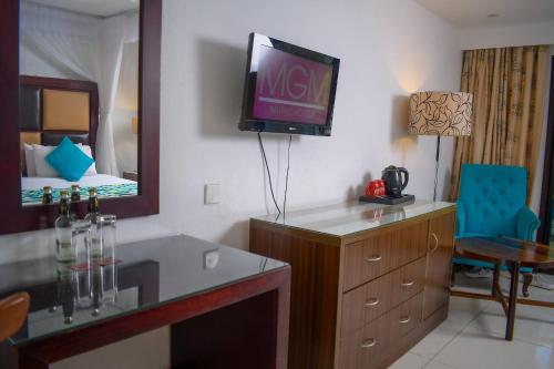 a room with a tv on the wall and a bedroom at Cocoa Luxury Resort, Nyali, Mombasa in Mombasa