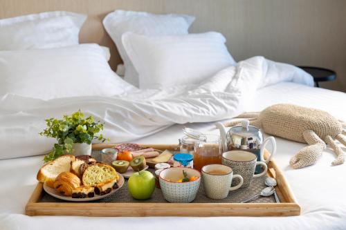 a tray of breakfast foods on a bed at Best Western Plus Hotel les Rives du Ter in Larmor-Plage