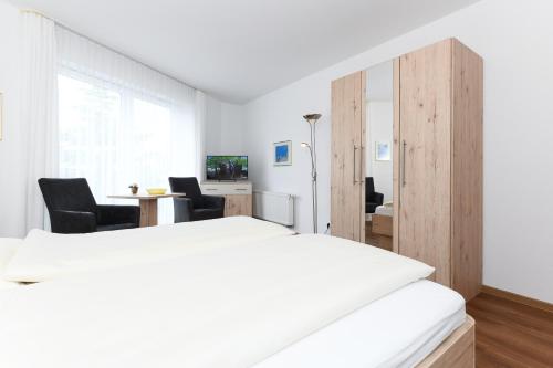a bedroom with a bed and a desk with chairs at Hotel-Pension Marlies in Neuharlingersiel