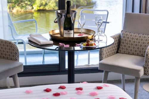a table with a bottle of wine and wine glasses at Best Western Plus Hotel les Rives du Ter in Larmor-Plage