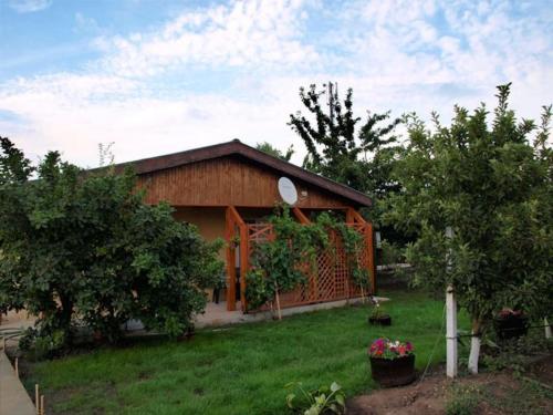 a small house in a yard with trees and grass at Къща бунгало Градината in Krapets