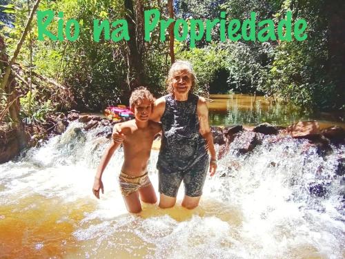 a woman and a boy standing in a waterfall at Chalé Rio Piscina Cozinha Área de Lazer Pertinho da CidadeMaravilha in Pirenópolis