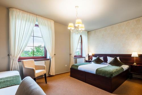 um quarto com uma cama, uma cadeira e 2 janelas em Hotel Plumlov em Mostkovice