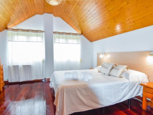 a bedroom with a large white bed with two windows at Espectacular casa con piscina y gran jardín in Navajeda