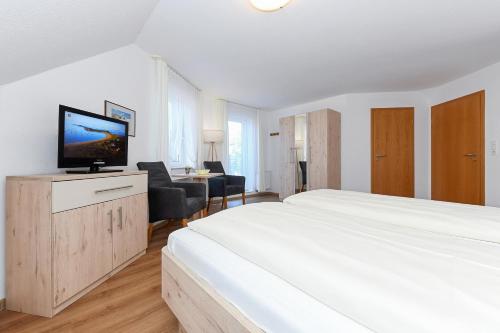 a white bedroom with a large bed and a desk at Hotel-Pension Marlies in Neuharlingersiel