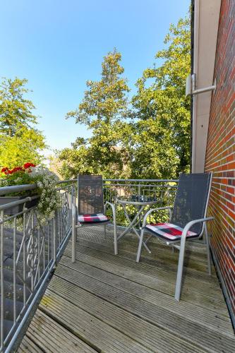two chairs sitting on a deck on a building at Hotel-Pension Marlies in Neuharlingersiel