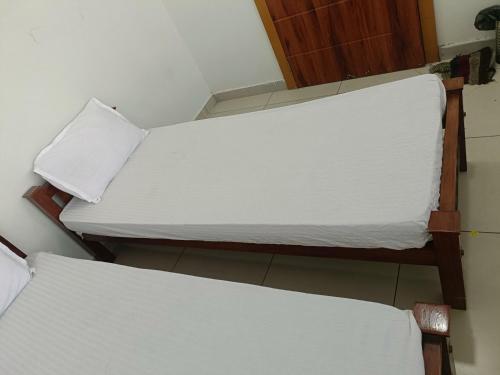 two beds in a room with white sheets at Grace Tourist Home in Ernakulam
