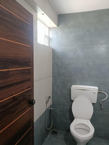 a bathroom with a toilet and a wooden door at Grace Tourist Home in Ernakulam