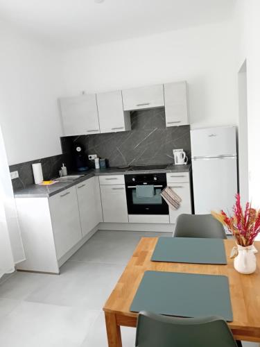 a kitchen with white cabinets and a wooden table at Lind-Appartments in Villach