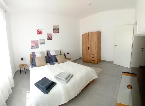 a white bedroom with a large bed with blue pillows at Lind-Appartments in Villach