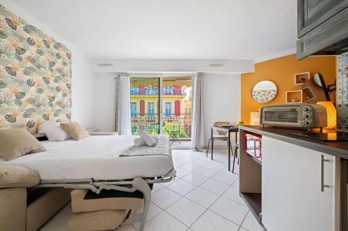 une chambre avec un lit et une cuisine avec un four micro-ondes dans l'établissement Victoria Beach - Charmant studio hyper centre ville de Menton - Mer au pied de l'immeuble, à Menton