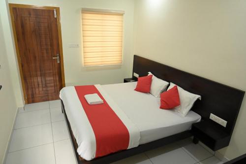 a bedroom with a bed with red and white pillows at Grace Tourist Home in Ernakulam