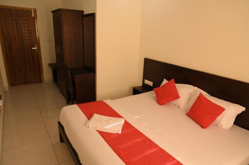 a bedroom with a bed with red and white pillows at Grace Tourist Home in Ernakulam