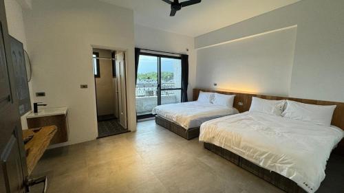 a hotel room with two beds and a balcony at Tianshe Xiangsui B&B in Hualien City