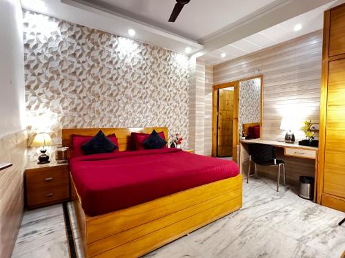 a bedroom with a bed with a red bedspread and a desk at Divine Inn Hotel Near Rajouri Garden Main Market in New Delhi