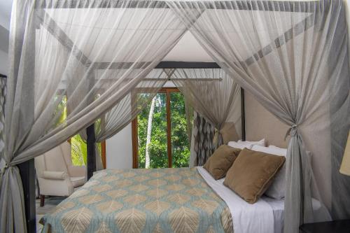 a bedroom with a bed with curtains and a window at Cocoa Luxury Resort, Nyali, Mombasa in Mombasa
