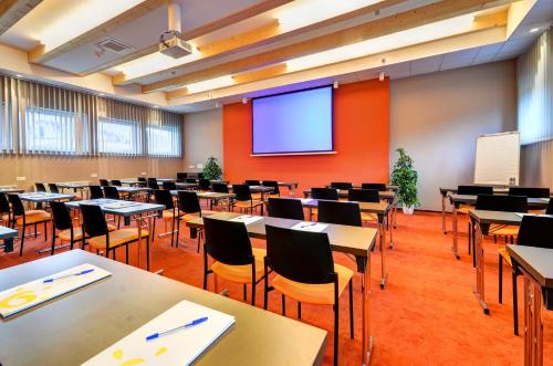 un aula vacía con mesas y sillas y una pantalla de proyección en Apartmány U stezek, en Lipová-lázně