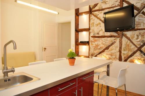 eine Küche mit einem Waschbecken und einem TV an der Wand in der Unterkunft Baixa Cosy in Lissabon