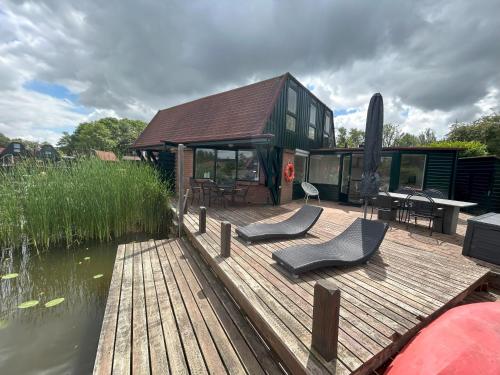 a house on a wooden deck next to a body of water at Lakeside Cottage De Rijd in Nieuwe-Niedorp