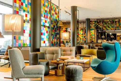 a lobby with chairs and a bar with colorful tiles at Motel One Köln-Neumarkt in Cologne