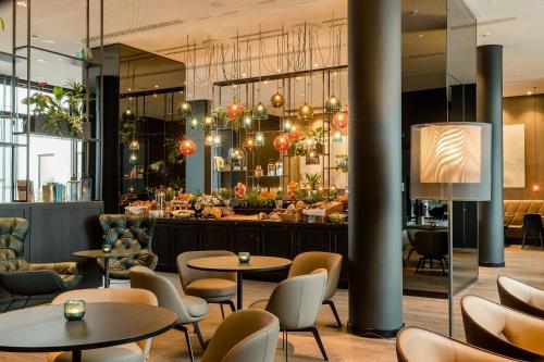 a restaurant with tables and chairs and a bar at Motel One Köln-Neumarkt in Cologne