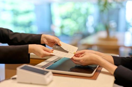 two people giving each other a credit card at The Royal Park Hotel Ginza 6-Chome in Tokyo