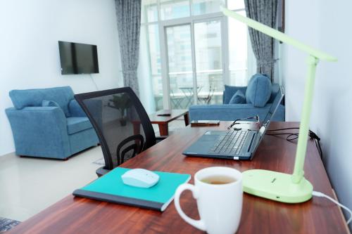 a desk with a laptop computer and a cup of coffee at Comfort in Sharjah