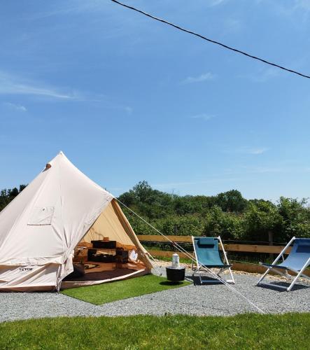 une tente et deux chaises pliantes sur l'herbe dans l'établissement La tente de l'atelier de la Gare, à Sigournais