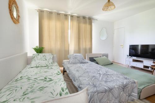 une chambre avec deux lits et une télévision à écran plat dans l'établissement Grand T1, 3 pers, à 8min de Paris, métro 13 et 14 