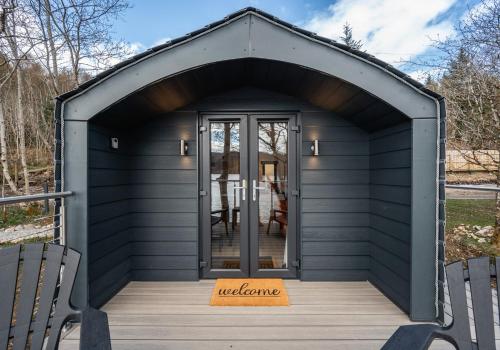a black shed with the door open on a deck at Nessie Pod in Fort Augustus