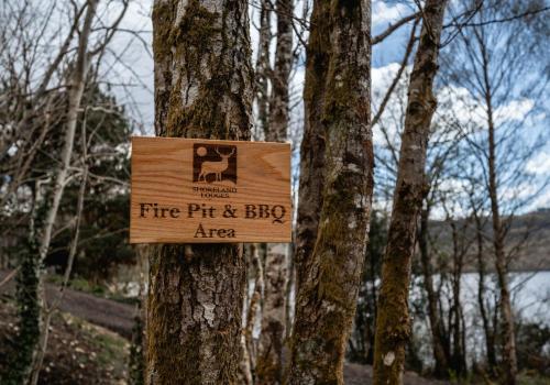 a fire pit and big area sign on a tree at Nessie Pod in Fort Augustus
