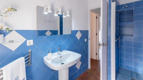 une salle de bain bleue avec un lavabo et un miroir dans l'établissement Casa La Primorosa El Gastor by Ruralidays, à El Gastor