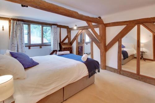 a bedroom with a large bed with wooden beams at DADIO's Barn - Indoor Swimming Pool 400 Years Old & Hot tub in Kent