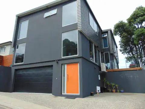 a house with an orange door and a garage at The perfect stop over in Wellington