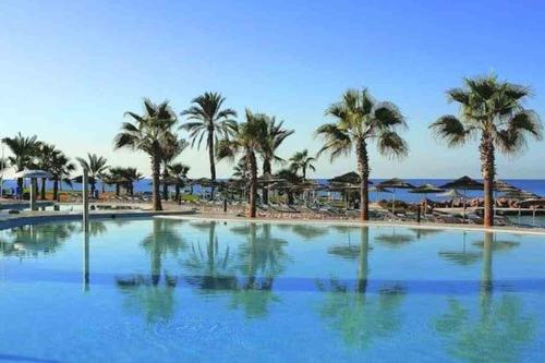 a large swimming pool next to a beach with palm trees at SPECIAL OFFER -70 Percent OFF - Sleep 5 - Best Location - Free Parking in Ayia Napa