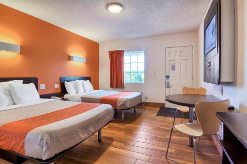 a hotel room with two beds and a table at Motel 6-Harrisonburg, VA - South in Harrisonburg