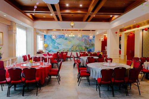 a banquet hall with tables and red chairs at Grand Swiss-Belhotel Melaka in Melaka