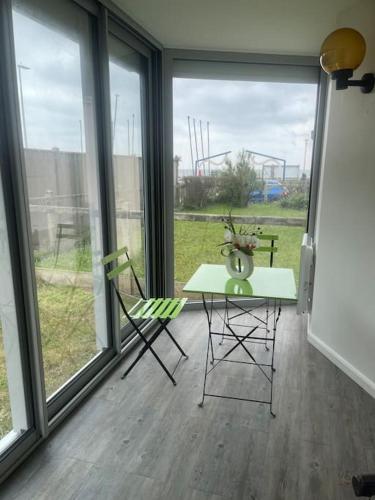 une table et deux chaises dans une pièce avec des fenêtres dans l'établissement Apparemment front de mer, à Ouistreham