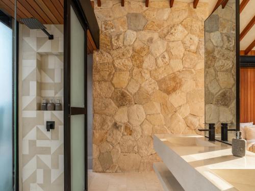 baño con 2 lavabos y pared de piedra en Blacksand Villas Echo Beach Canggu B4, en Canggu