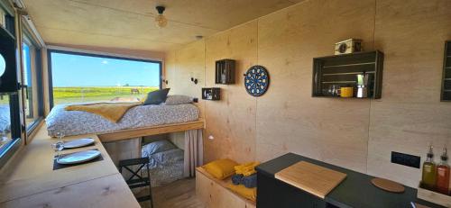 ein kleines Haus mit einem Bett und einem Schreibtisch in der Unterkunft Tiny House La Cavalerie, au milieu des chevaux ! in Annouville-Vilmesnil