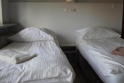 two beds in a room with white sheets and pillows at Bon Ton in Szczecin
