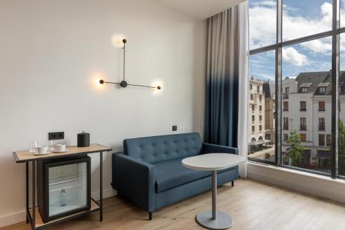 a living room with a blue couch and a window at Aloft Hotel, By Marriott in Dijon